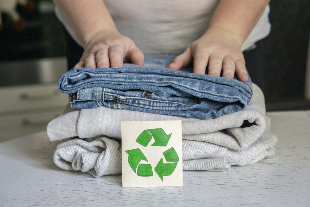 Affordable Sustainable Clothing concept. A stack of clothes is on the recycling table. Collection of clothes for recycling.