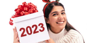 Excited young women wearing deer antlers and holding a giftbox that says 2023