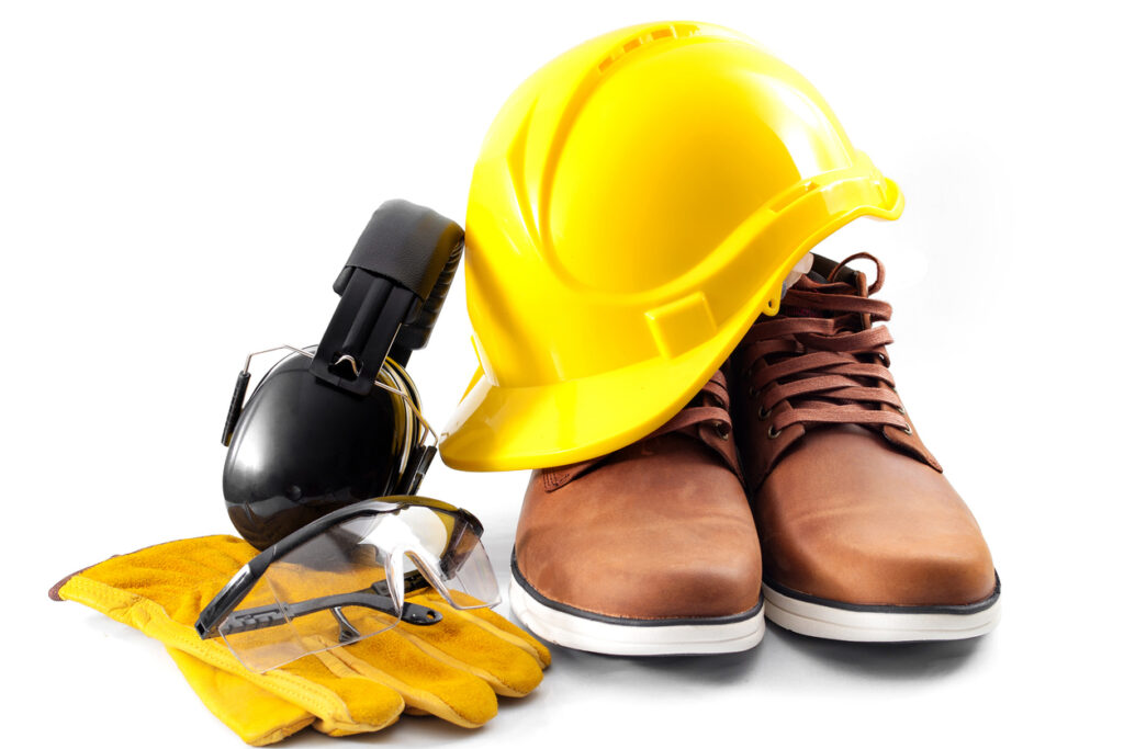 Safety apparel including yellow hard hat, boots, gloves, and protective eyewear.