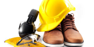 Safety apparel including yellow hard hat, boots, gloves, and protective eyewear.