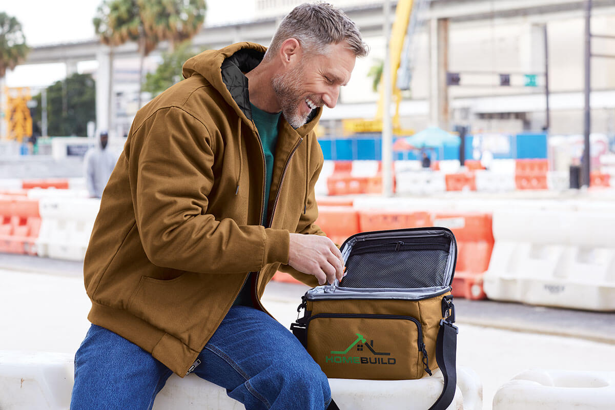Man holding an RCHQ-branded lunch cooler bag showing custom corporate apparel and work uniform options.