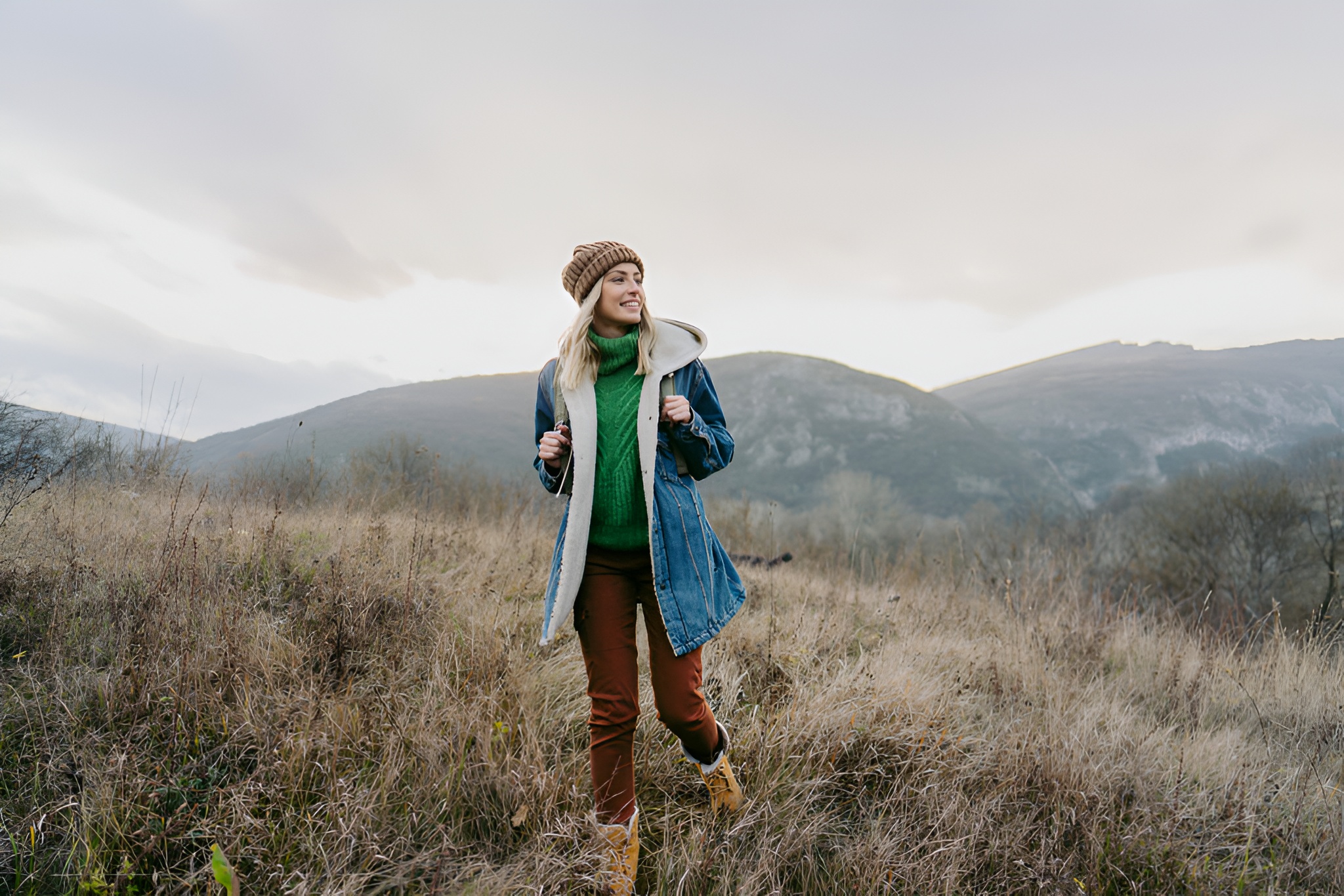 Woman in ethically sourced, warm, and durable winter wear from Righteous hiking in a vast natural landscape.