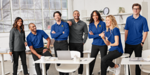 Office team in matching polos and quarter-zips by Righteous Clothing Agency, gathered around desks.