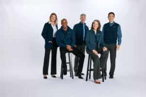 Team models navy branded uniforms by Righteous Clothing Agency, featuring cardigans, vests, and jackets.