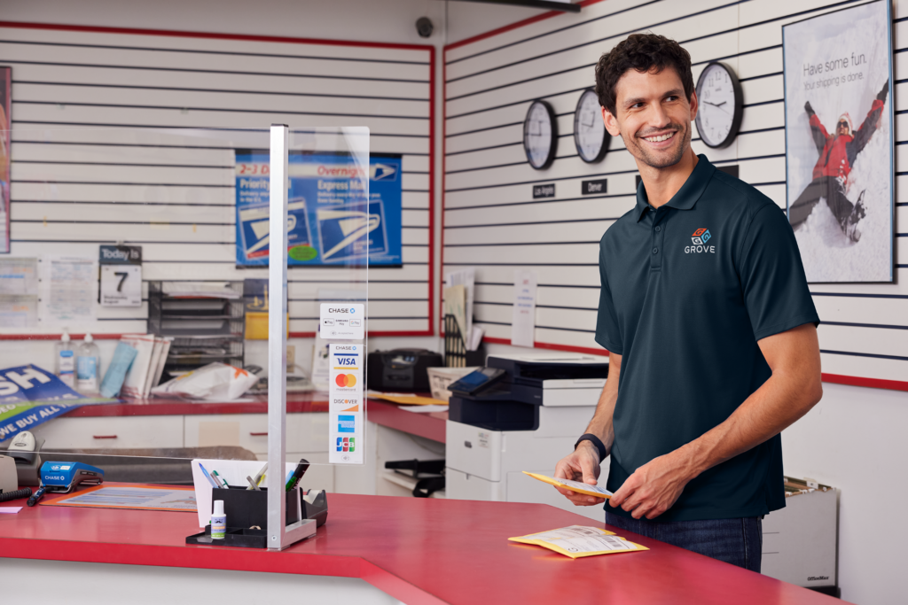 Shipping counter staffer in logo polo by Righteous Clothing Agency prepares packages behind a service desk.