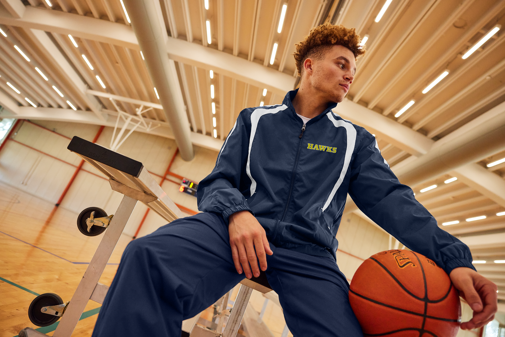 Righteous branded navy tracksuit worn by a basketball player holding a basketball in a gymnasium setting.