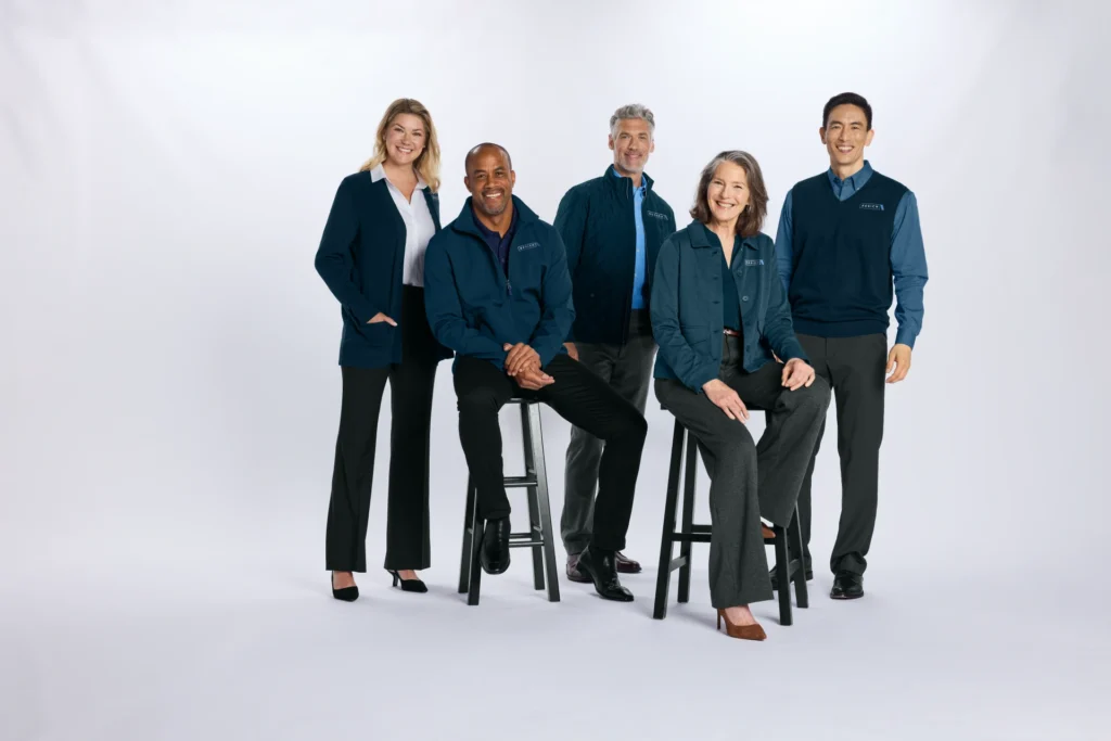 Five professionals in coordinated navy workwear from Righteous pose with a navy tote bag.